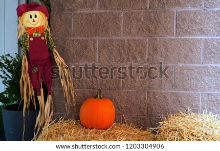 Harvest display with scarecrow and hay bales. Thanksgiving, harvest and autumn decoration. Scarecrow and bail of hay in USA.                             