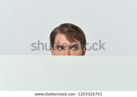 man looks out from behind a white mockup                        