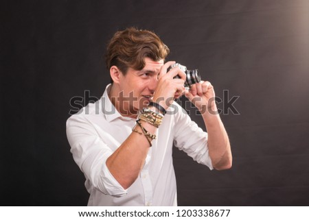 People, photographer and vintage concept - man searching for an interesting subject for his photo holding a vintage camera on brown background
