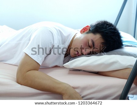Asia young man wearing a white t-shirt sleeping comfortable on the bed, white background. closeup image.