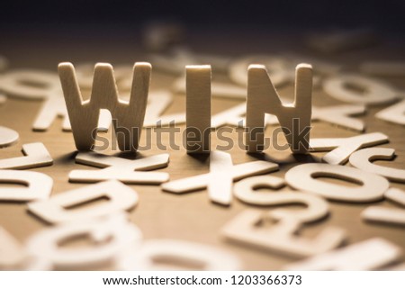 The wood is the word win, The wooden letters are scattered around, About success. Royalty-Free Stock Photo #1203366373