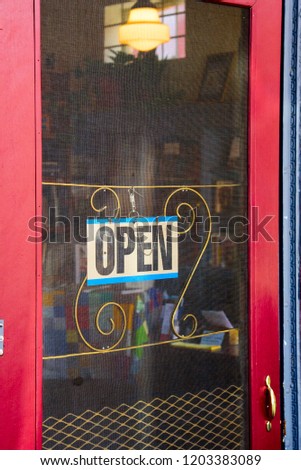 Open for business. A red vintage wooden door with an "Open" sign welcomes customers into a retail shop.