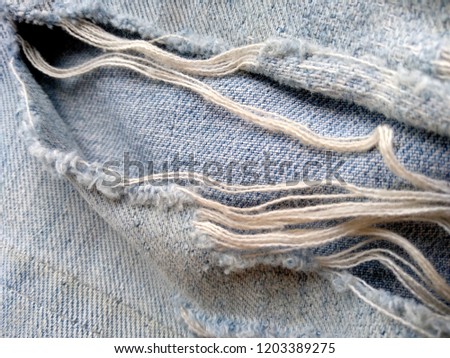 The texture of ripped denim jeans. Torn jeans or jeans fabric that has been damaged, torn and hole.