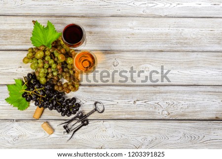 wine with branches of white grapes. On a wooden table.