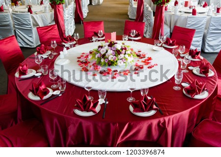Beautiful flowers are placed on the table covered with red tablecloth, wedding hall
