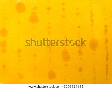Selective focus with closeup : Spots and lines of grease stains from oil generated by bars of colorful clays for kid's creative playing soaking on light and bright yellow orange art grossy paper box