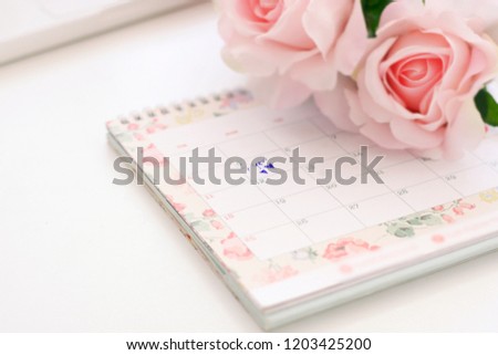 The wedding anniversary is in the calendar and there are pink roses on the table.