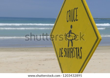 Caution surfers cossing sign, Galapagos Islands, with waves in bacgroudn.
