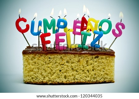 letter-shaped candles of different colors forming sentence cumpleanos feliz, happy birthday in spanish, on a cake