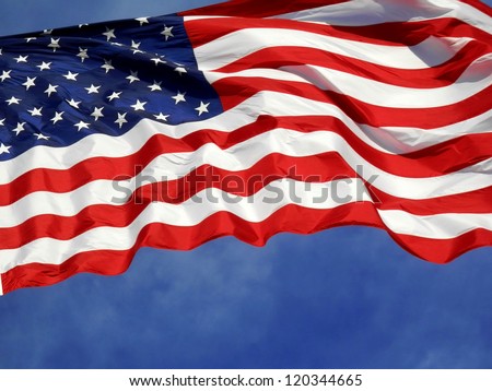 United States flag blows in the wind against a blue sky