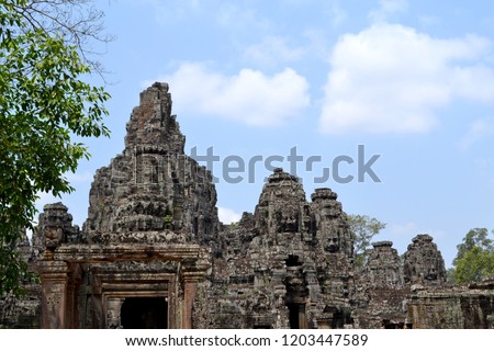 The Bayon is a richly decorated Khmer temple at Angkor in Cambodia. Faces of Buddha carved out of stone. Image of the Khmer king. Ruins of ancient Asian temples in the jungle. Unique bas-reliefs