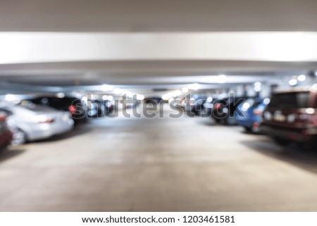 Out of focus parking garage with cars and trucks parked in all of the parking spaces.