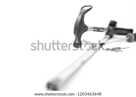Hand tools on white background, hammer, screwdriver, ruler, pencil and nails, shallow depth of field, focus on the pencils tip in black and white.