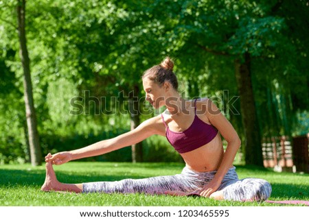 Full length shot of beautiful young female yoga instructor practicing yoga outdoor.