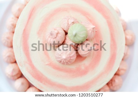 Beautiful and delicious strawberry cake with pink and green meringues on top, on a white plate close up