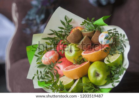 Bouquet of flowers and fresh citrus fruits wrapped in coarse paper