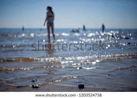 Blurred unfocused silhouettes of woman and other people on the beach with backlight, glare and highlights, web banier, background