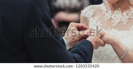 a man wearing a wedding ring for his bride during the ceremony and the sacrament of the wedding. A pair of pairs