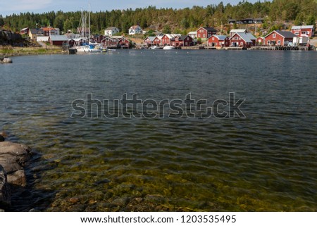 Seashore in foreground and a little fishing village in background, picture from High Coast Area in Northern Sweden.