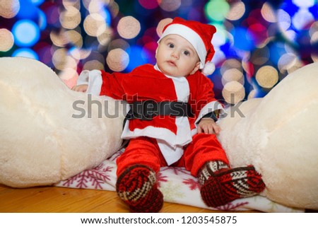 Cute baby wearing santa claus costume on a couch at home in christmas