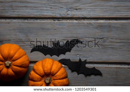 Halloween pumpkins and black vampire bats on a wooden background