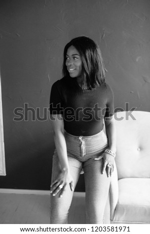 Close up shot of pleasant looking African American female has delighted look, healthy dark skin, poses indoor on sofa, has happy expression, expresses positive emotions. . black and white portrait