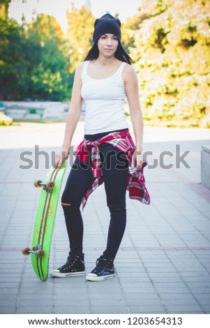 Beautiful woman with a skateboard on the street, soft focus background