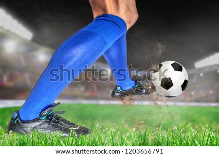 Soccer player in action with football in brightly lit outdoor stadium. Focus on foreground and soccer ball with shallow depth of field on background and copy space.