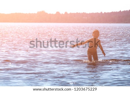 little kid play in water and making splash child swim in lake or river and have fun