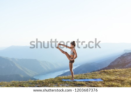 Young attractive girl doing yoga on yoga mat. Enjoying practicing ashtanga out in the nature