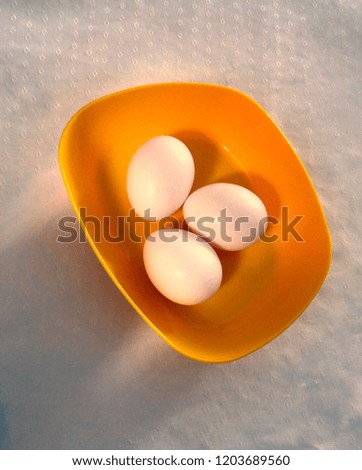 Three chicken eggs in a bowl yellow
