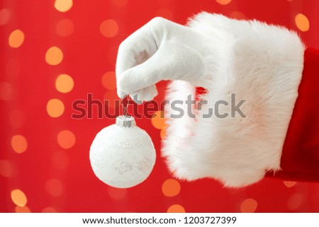 Santa holding a Christmas bauble on a shiny light red background