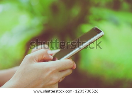 Woman hand using smartphone with nature green  beautiful background. Business, financial, trade stock maket and social network concept.