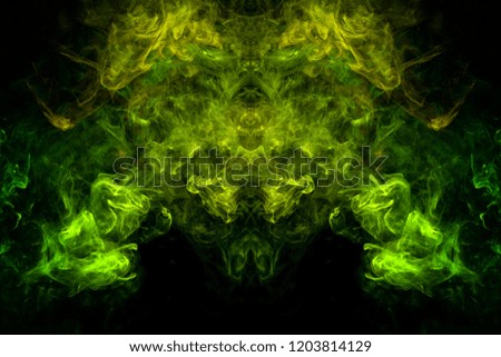 Fantasy print for clothes: t-shirts, sweatshirts. Thick colorful smoke of yellow, green colors smoke in the form of a skull, monster, dragon on a black isolated background. Background from the smoke