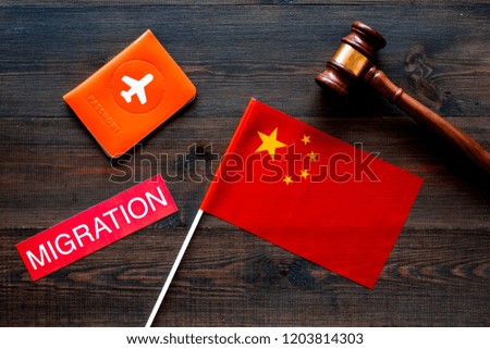 Immigration to China concept. Text innigration near passport cover and chinese flag, judge hammer on dark wooden background top view