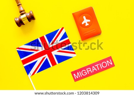 Immigration to Britain concept. Text immigration near passport cover and british flag, hammer on yellow background top view