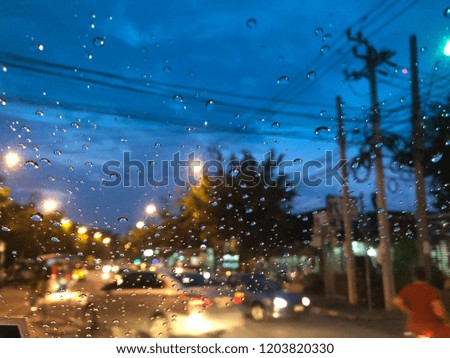 Colorful bokeh with street light at night. Raindrops on car windshield, traffic in the city on a rainy day. Blur background. Selective focus.
