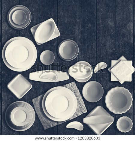 White porcelain dishes set on rustic wooden table. Top view, copy space. Toned.