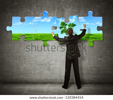 Businessman making a puzzle on the wall with  picture of nature