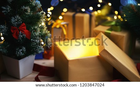 Open Christmas Box Gift Besides Small Christmas Tree. Glowing Light