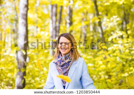 Nature, season and people concept - young woman laughing at the autumn park