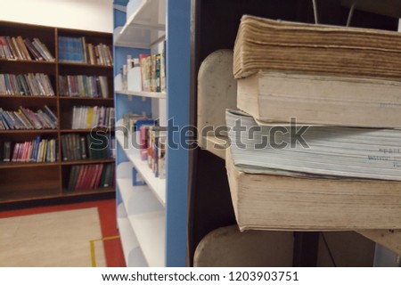 Book stack on desk and blurred bookshelf in the library room, education background, back to school concept. 
