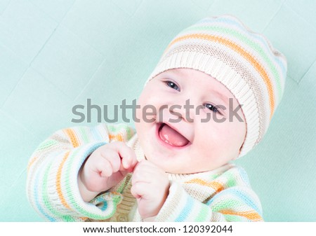 Happy smiling baby in a warm striped knitted sweater and hat