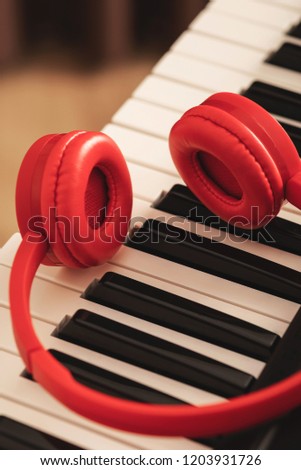 Compose or music listening. Red headphones over synthesizer keyboard