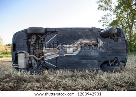 car on its rolled onto its side in a field after going to fast around corner