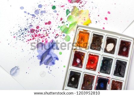 Watercolor paint set with swatches of paint splatter on paper 