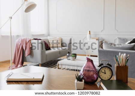 Table with notebook, small plant in pot, glass vase, clock and pencils in cup, real photo with copy space