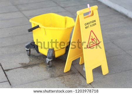 Bucket and caution sign on wet floor.