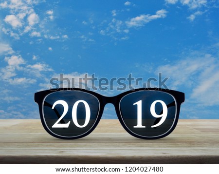 2019 white text with black eye glasses on wooden table over blue sky with white clouds, Business vision happy new year 2019 concept