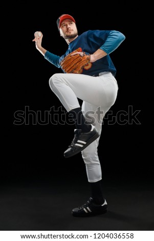 Baseball player throwing a fastball. Portrait of the pitcher in wind up position on black background.